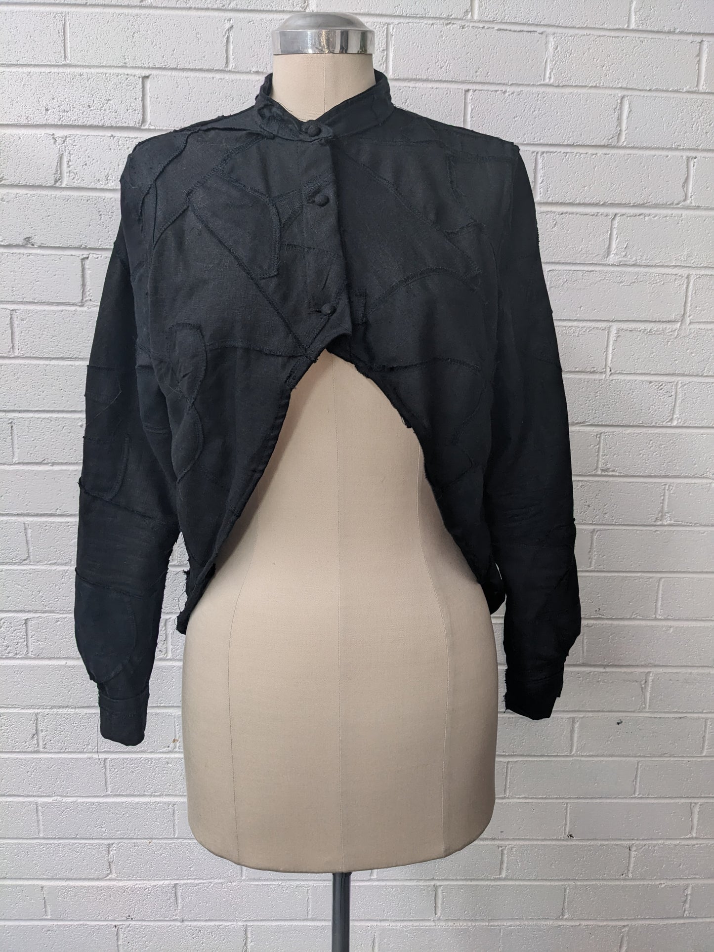 Black quilted shirt on mannequin in front of brick wall