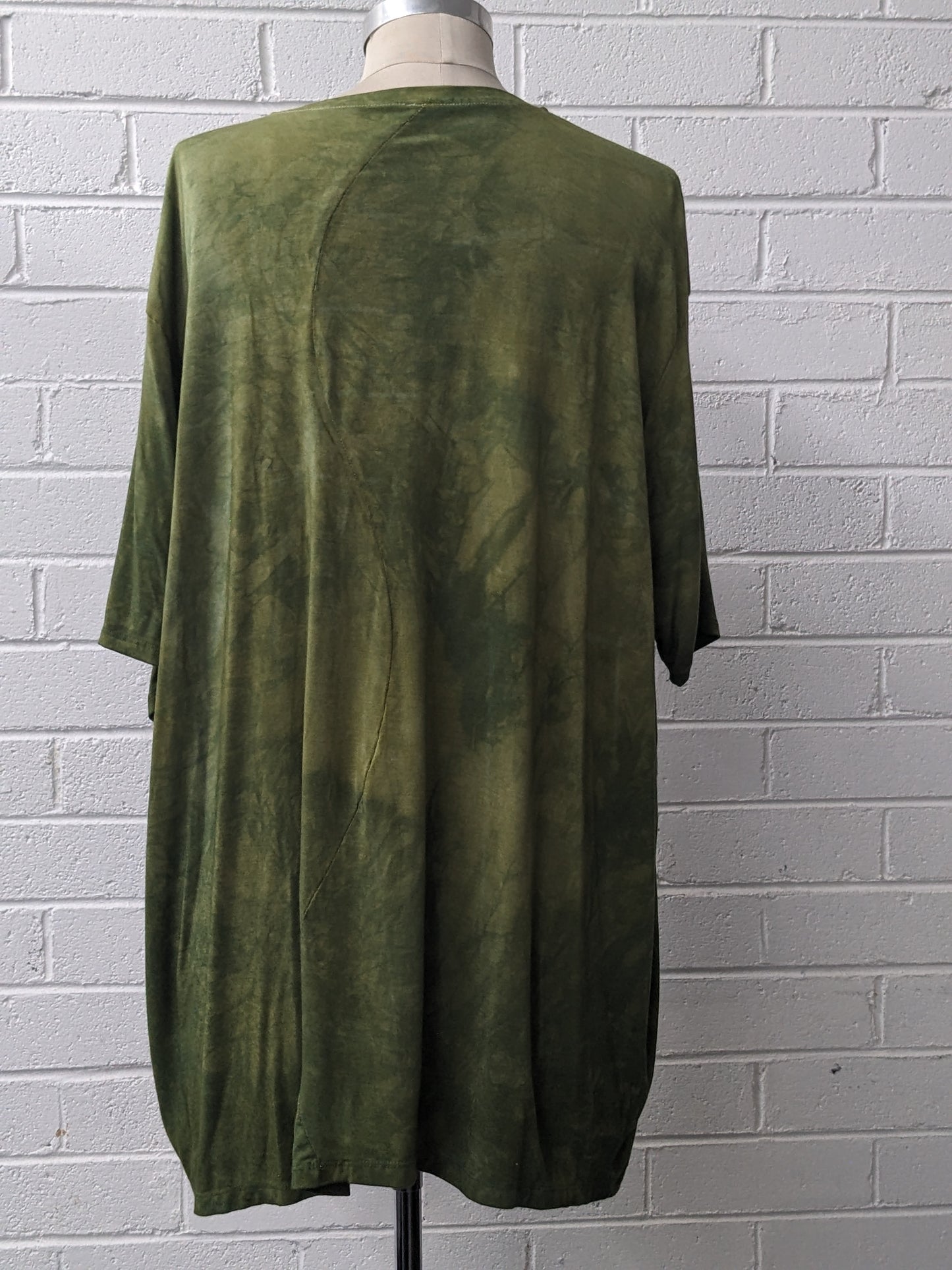 Green shirt on a mannequin against a gray brick wall