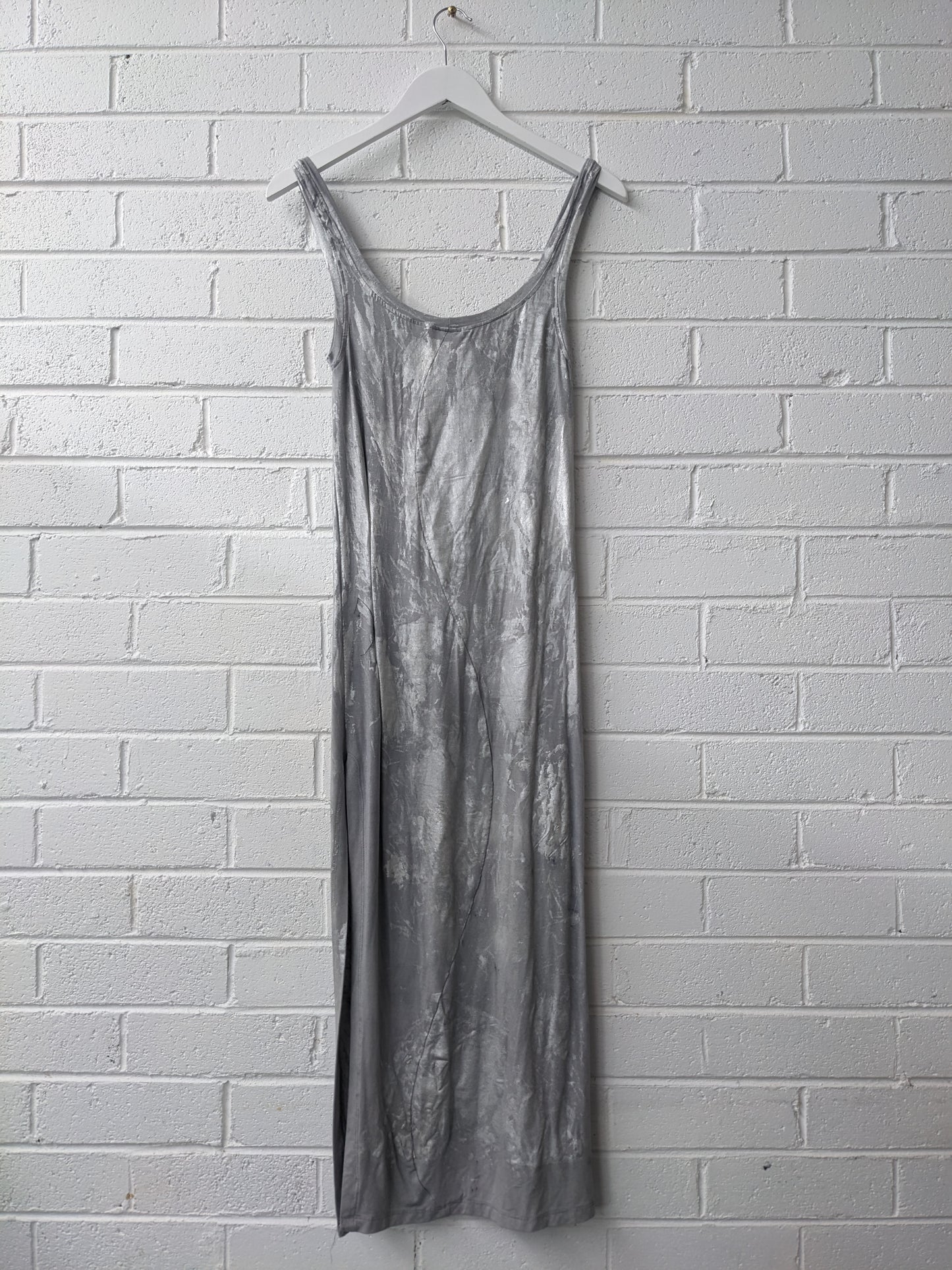 Silver dress on white hanger against brick wall 