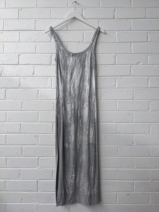 Silver dress on white hanger against brick wall 