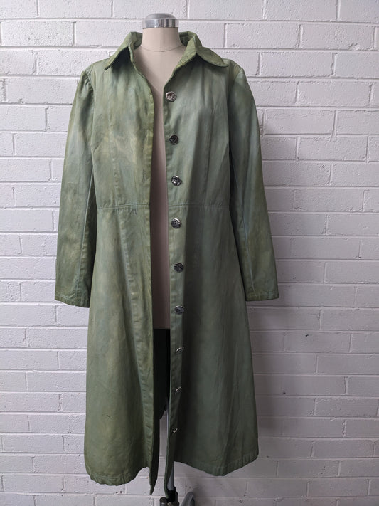 Hand dyed green jacket on mannequin against brick wall 